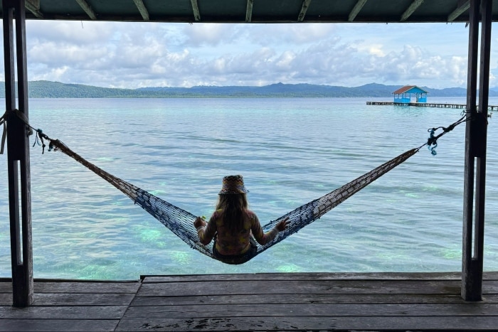 En la imagen se ve una niña en una hamaca mirando al mar en Raja Ampat