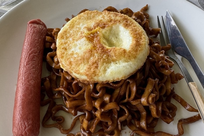 En la foto se ven unos noodles, nuevo y salchicha. La foto está sacada en el comedor del Río Kinabatangan 
en el homestay Osman