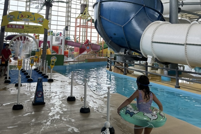 En la foto se ve a una niña con flotador y de fondo un parque acuático. Spa World Osaka